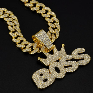 Macro shot of gold Cuban chain necklace with iced out BOSS crown pendant and rhinestones