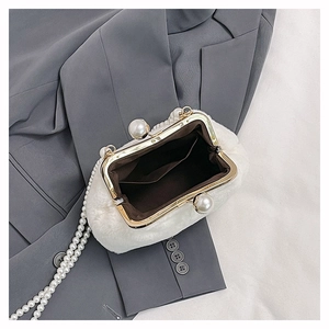 Detail of white plush shell bag featuring pearl handle and secure metal frame closure