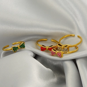 Detail of adjustable bow rings with green, red, pink and white micro-pave crystals