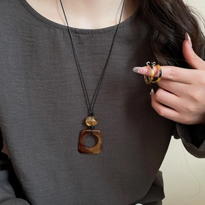Detail of model wearing leopard print resin pendant necklace and coordinated stackable rings