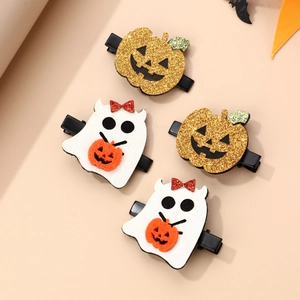 Detail of Halloween hair clips with gold glitter pumpkin and white ghost on beige background