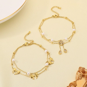 Double-layered gold bow and clover bracelet set with pearls on a decorative tray