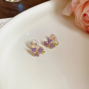 Detailed macro view of purple flower clip-on earrings with soft silicone pads and gold metal