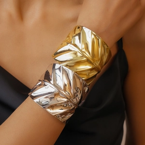 Macro detail of wide metal cuffs with leaf texture in polished gold and silver finishes