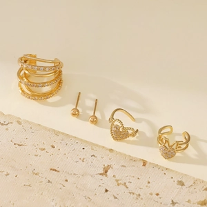 Detail of elegant gold layered ear cuffs and heart studs with zircon on stone