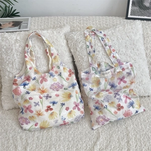 Detail of floral mesh tote bags with vibrant flower prints on white plush surface