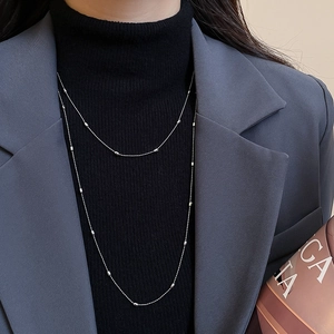Close-up of minimalist double-layer silver beaded necklace on a black turtleneck sweater
