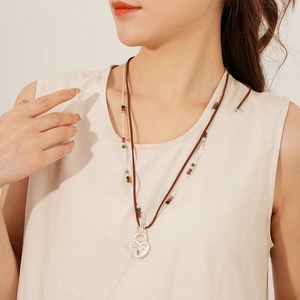 Close-up of double-layer necklace with brown leather cord, heart lock and colorful beads