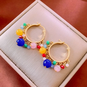 Macro detail of multi-colored beaded hoop earrings with gold finish in a gift box