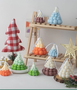 Variety of Christmas tree scented candles with gift ribbons on a rustic wooden shelf