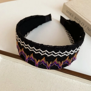 Détail d'un serre-tête tissé noir avec broderie vagues colorées et doublure intérieure