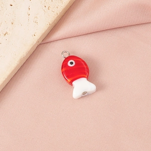 Detailed view of a handmade red and white glass fish pendant on pink silk and stone