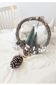 Detail view of a rustic Christmas wreath with snowy pinecones and a miniature house