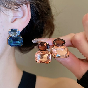 Detailed view of luxury geometric crystal earrings featuring blue and pink stone clusters