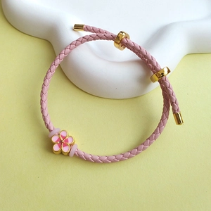 Pink braided PU leather bracelet with gold metal clasp and a delicate floral charm