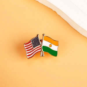 Detail of metal brooch featuring crossed American and Niger flags with gold finish