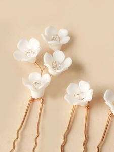 Detail of handmade white ceramic flower hair pins with crystals and gold wire stems