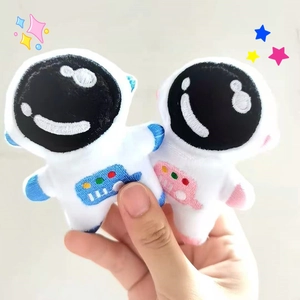 Hand holding white plush astronaut brooches with blue and pink embroidered details