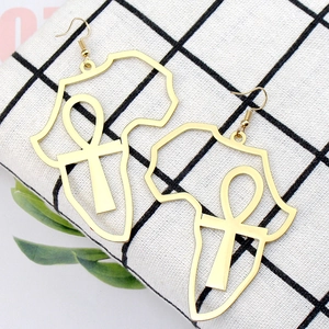 Détail de boucles d'oreilles dorées carte de l'Afrique et Ankh sur tissu à carreaux