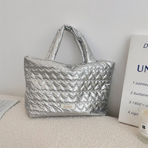 Close-up of silver heart-quilted tote bag fabric with metallic luster and brand label