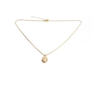 Detail of a golden heart lock necklace with flame patterns on a plain white background