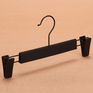 Detail of adjustable clips on a black plastic trousers hanger with sturdy metal hook
