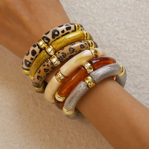 Close-up of leopard print acrylic bracelets and gold glitter bangles on a model's wrist
