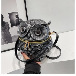 Close-up of owl-shaped crossbody bag featuring metallic black feathers and gold zipper details