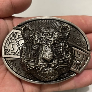 Close-up of vintage silver tiger head belt buckle with detailed high-relief metal carving