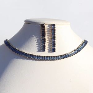 Detailed macro of gold-plated necklace and earrings set with rectangle blue cubic zirconia