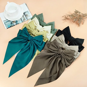 Elegant oversized satin bow hair clips in multiple Morandi colors on a warm backdrop