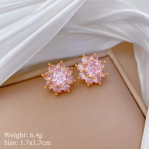 Macro shot of pink floral stud earrings with gold plating on a silk background