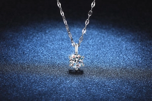 Detailed macro shot of a six-prong set one-carat moissanite pendant on a silver chain