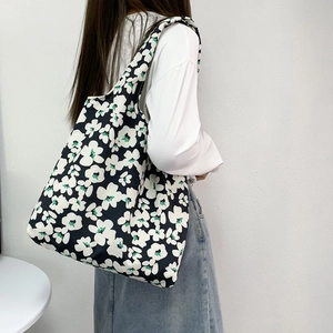 Detail of floral canvas tote bag with black and white print on a female shoulder