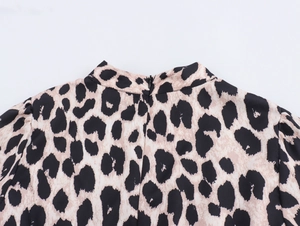 Detailed view of leopard print dress featuring high collar, invisible back zipper and puff sleeves