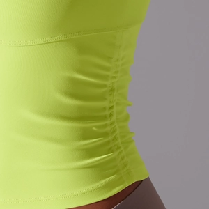 Détail de la couture latérale froncée sur haut de yoga vert fluo en tissu extensible