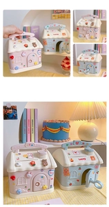 Detail view of pink and blue house-shaped piggy bank with cute 3D stickers and handle