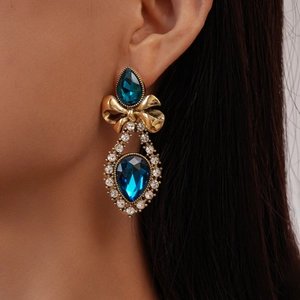 Detailed view of vintage bow earrings with dark blue teardrop stones and micro-inlaid crystals