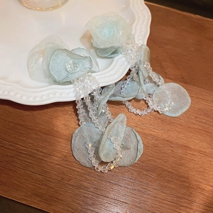 Détail de boucles d'oreilles fleur en tulle vert clair avec pampille en cristal