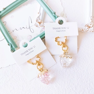 Detailed close-up of colorful translucent strawberry charms with sakura metal hooks