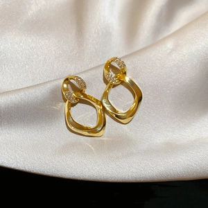 Detailed view of gold geometric interlocking earrings with zircon inlay on champagne silk