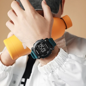 Detail of waterproof digital sports watch with green silicone strap and orange water bottle