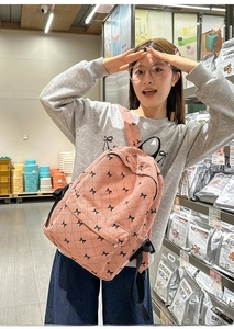 Pink corduroy backpack with black ribbon patterns worn by a student in a casual setting