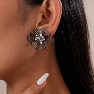 Close-up of model wearing black hollow flower stud earrings with a central sparkling gemstone