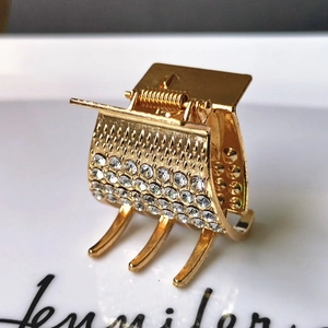 Golden alloy claw clip with rows of sparkling rhinestones shown from a 45-degree angle