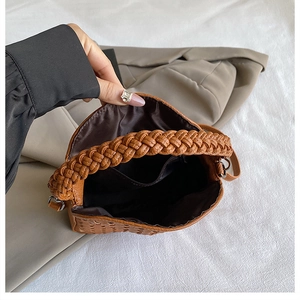 Detail of brown woven handbag showing black fabric lining and internal pocket structure
