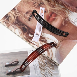 Detailed close-up of plastic banana hair clips in black, white, and tortoiseshell colors