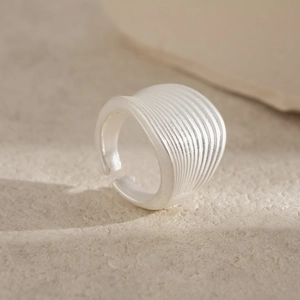Macro detail of silver alloy ring featuring textured brushed matte finish and open design