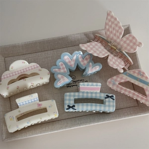 Floral and plaid hair claws in pink and blue tones on a fabric display tray