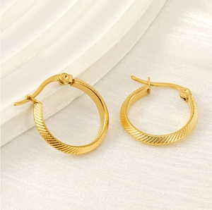 Macro detail of gold 18K stainless steel hoop earrings with textured striped finish